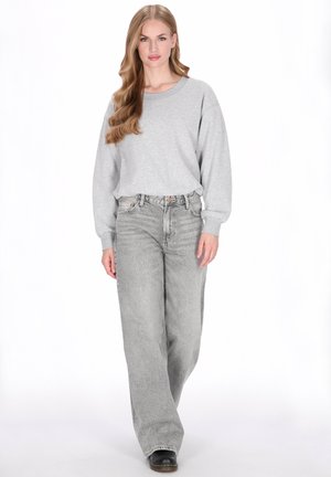Lysegrå oversized sweatshirt kombineret med lysegrå jeans med høj talje og vide ben. Sort fodtøj fuldender looket.
