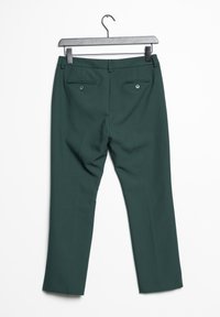 Donkergroene dresspants aan een metalen hanger, met de achterkant zichtbaar waarop knoopzakken en riemlussen zijn te zien.