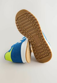 Baskets de sport bleu et vert avec une tige en daim et en maille. Accent blanc et semelle en caoutchouc texturée avec un motif de bande de roulement.