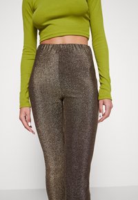 Legging korkeavyötäröiset, hohtavat ruskeat, joissa on sileä pinta, venyvä vyötärö ja metallinen hohde erottuvan ilmeen luomiseksi.