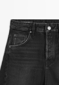 Jeans in denim nero con vita alta, design classico a cinque tasche, accessori in argento e una texture sottile nel tessuto.