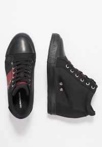 Černé vysoké tenisky s plátěným svrškem, gumovou špičkou a červeným akcentem. Obsahují kovové očko a strukturovanou podrážku.