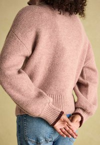 Rosa gestrickter Pullover mit geripptem Saum und Bündchen. Weicher Stoff, lockere Passform und kontrastierende braune Akzente an den Bündchen.