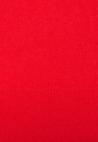 Tissu en tricot rouge avec une texture lisse et une bordure côtelée en bas. Couleur uniforme sans motifs ni détails matériels visibles.