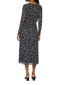 Schwarzes durchsichtiger Kleid mit weißem Blumenmuster, langen Ärmeln, elastischem Bund und gewelltem Saum. Tragen mit schwarzen Blockabsatzsandalen.
