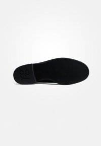 Sole in gomma nera con un motivo texture, forma piatta e un logo in rilievo sottile. Si notano bordi lisci e una finitura opaca.