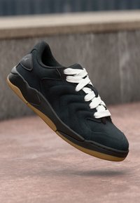 Sorte nubuck sneakers med et teksturert sikksakk-design, kontrasterende hvite lisser og en gummigummi-såle. Har rund tå og polstret krage.