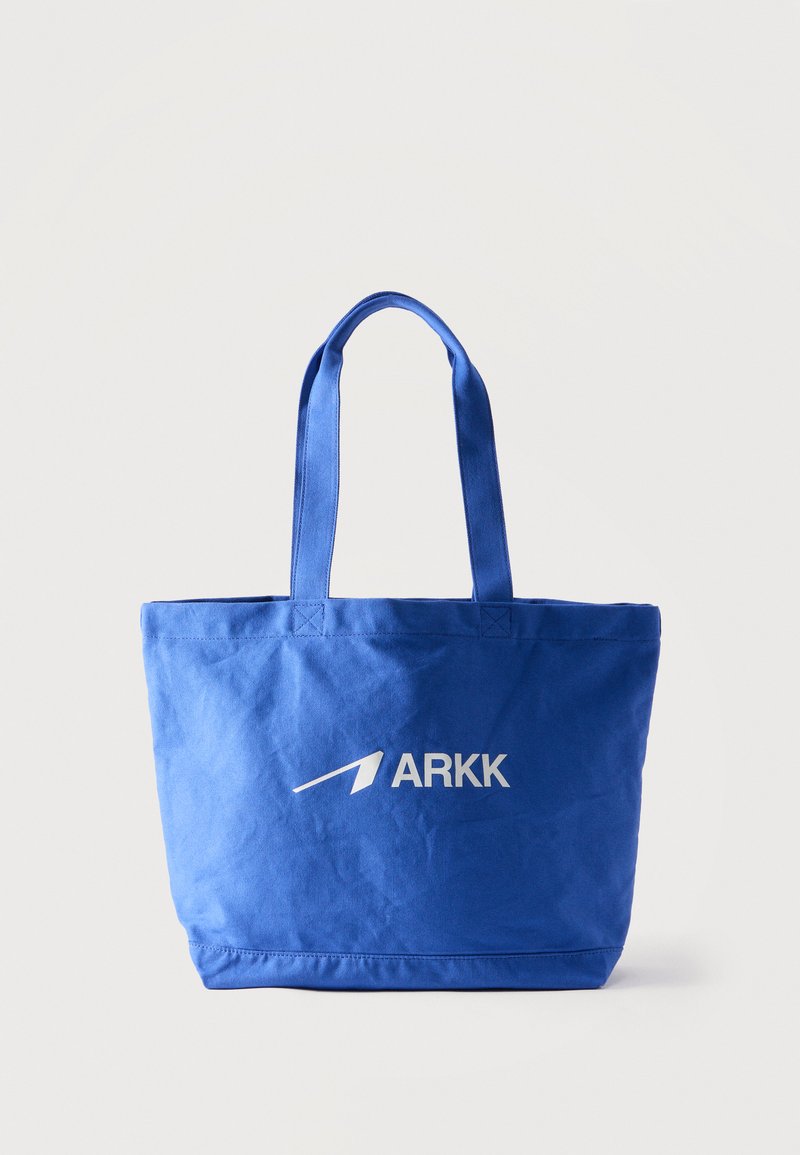 Μπλε τσάντα υφασμάτινη με δύο λαβές, με λευκό λογότυπο ARKK στο κέντρο της εμπρός πλευράς πάνω σε μια απλή φόντο.
