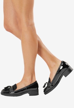 Mocassins en cuir verni noir avec un bout rond, des franges décoratives et un petit talon bloc texturé. Surface lisse et design épuré.