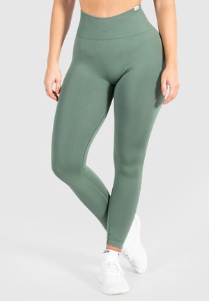 Vihreät korkeavyötäröiset legginsit, jotka on valmistettu joustavasta kankaasta ja joissa on sileä pinta. Legginsit ovat varustettu ribatulla vyötärönauhalla ja saumoilla.
