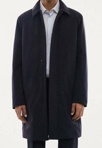 Abrigo azul marino hecho de tela suave, con cierre de botones, mangas largas y cuello clásico. Diseño minimalista sin patrones visibles.