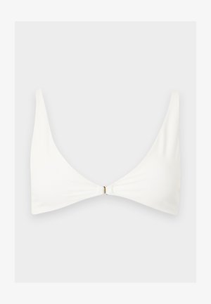 Λευκό μινιμαλιστικό τοπ μπικίνι με λεπτές τιράντες στους ώμους και μικρό χρυσό κούμπωμα στο κέντρο μπροστά, σε απλό ανοιχτό φόντο.