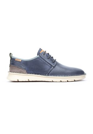 Chaussure en cuir marine avec un profil bas, doublure bleu clair et semelle beige. Présente des coutures décoratives et une section texturée près du talon.