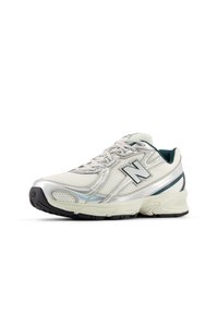 Λευκό αθλητικό παπούτσι με επάνω μέρος από δίχτυ, ασημί λεπτομέρειες και μαύρη καουτσούκ σόλα. Διαθέτει δέσιμο με κορδόνια και υφασμένα στοιχεία στις πλευρές.