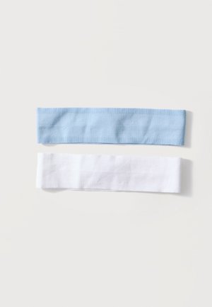 Dve pruhované látkové čelenky, jedna svetlomodrá a jedna biela, rozložené na jednoduchom bielom pozadí.
