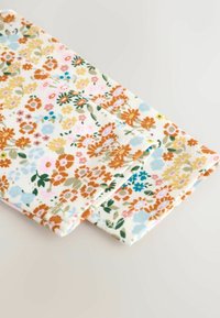 Gros plan d’un tissu plié avec un petit motif floral en orange, jaune, bleu, rose et vert sur fond blanc.