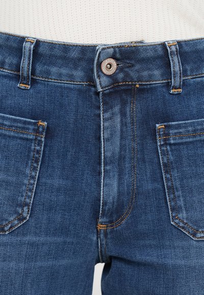 Jeans in denim di colore blu scuro con un design classico, dotati di chiusura a bottoni, cinque tasche e cuciture arancioni a contrasto.