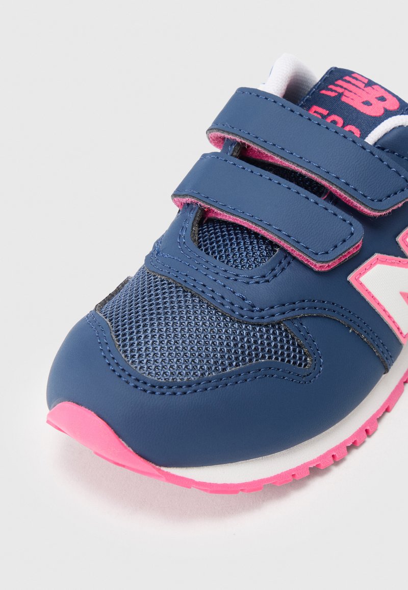 Chaussure pour enfant en synthétique bleu avec des accents en mesh, semelle rose et bandes Velcro. Présente un logo blanc bien visible sur le côté.