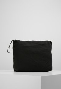 Svart tygväska med rektangulär form. Har en dragkedjestängning och ett öglahandtag. Slät textur utan synliga mönster eller accentueringar.