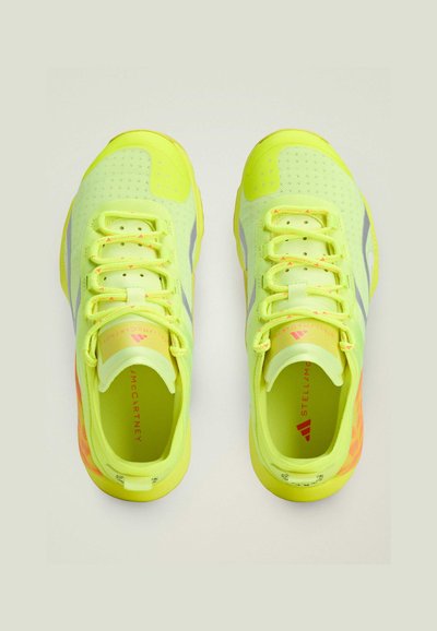 Neon yellow athletic shoes with a textured upper, lace closure, reflective accents, and contrasting orange detailing on the sole.