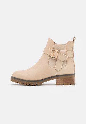 Beige Knöchelstiefel mit Wildleder-Oberfläche, runder Zehenform, elastischen Seitenpaneelen, dekorativem Riemen mit goldfarbener Schnalle und strukturiertem Blockabsatz.