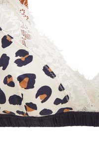 Soutien-gorge à imprimé léopard avec un fond crème, doté de dentelle, d'une texture douce et d'une bande élastique noire en bas.