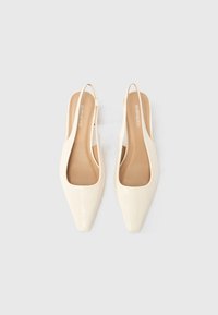 Chaussures slingback en cuir verni blanc avec bouts pointus, design minimaliste et texture lisse. L'intérieur comporte une semelle beige.