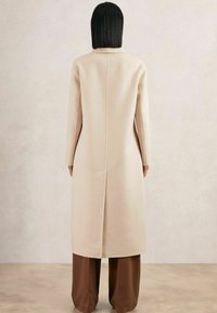 Beige wollen jas met lange mouwen, een rechte snit, split aan de achterkant en een minimalistisch ontwerp. Draag hem over brown wijde broek.