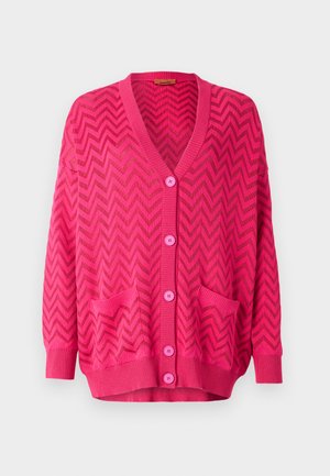 Rozā adīta veste ar zigzaga rakstu, ar V-veida kakla izgriezumu, garām piedurknēm, piecām pogām un divām priekšējām kabatām.