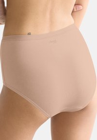 Beige højtaljede undertøj lavet af blødt stof med glat tekstur. Har en logo på taljebåndet og minimale sømme for et sømløst udseende.