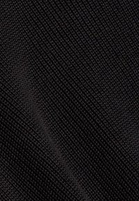 Gros plan sur un tissu noir étroitement tissé avec une texture côtelée diagonale et un motif tricoté finement détaillé.