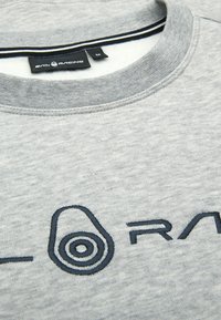 Sudadera gris con cuello redondo, presenta un logo de marca bordado en azul marino en la parte delantera y un detalle de rayas en contraste en el interior del cuello.