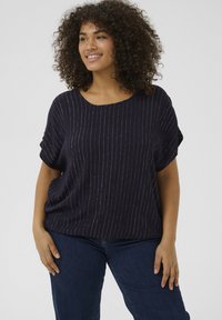 Haut bleu marine à coupe ample, avec un décolleté arrondi et des rayures verticales argentées. Tissu doux avec une texture légère.