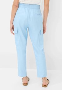 Light blue cargo pants with a cinched waist, two side cargo pockets, and two back pockets. Made of soft, lightweight fabric with a straight leg.