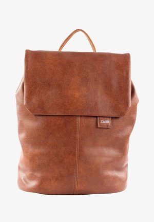 Brown leather backpack with a fold-over flap, smooth texture, stitched detailing, and a top handle. Features a brand label on the front.