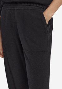 Svarta, texturerade byxor med en avslappnad passform, utrustade med sidofickor och en ribbad midjeresår för komfort och lätthet att bära.