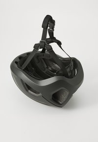 Czarny kask rowerowy o aerodynamicznym kształcie, z wieloma otworami wentylacyjnymi i regulowanymi czarnymi paskami dla zapewnienia bezpiecznego dopasowania. Widoczna wewnętrzna pianka amortyzująca.