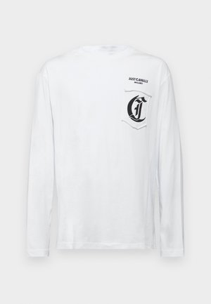 Hvit langermet skjorte laget av bomull som har rund hals og en lomme med en svart grafisk logo på venstre side.