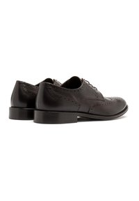 Brązowe skórzane buty wizytowe z zapięciem typu wingtip, z detalami brogu, gładką powierzchnią i piętą nałożoną warstwowo. Sznurowadła widoczne z przodu.