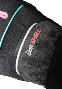 Schwarzer Softshell-Stoff mit Akzenten in Pink und Türkis, ausgestattet mit strukturierten Details und weißen Nähten, auf denen das Logo "Soft SHELL" deutlich sichtbar ist.