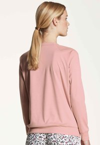 Light pink sweatshirt with a relaxed fit, round neckline, and ribbed cuffs. Smooth texture, featuring drop shoulder seams and a simple design.