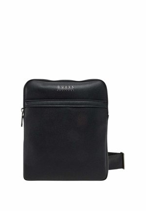 Sac bandoulière rectangulaire noir avec poche zippée à l'avant et sangle ajustable, avec un petit logo "GUESS" en haut au centre.