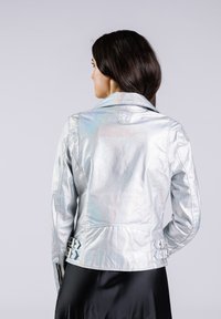 Veste métallique argentée au design ajusté, dotée d'un col cranté, d'accents en boucle sur les côtés et d'une surface texturée.
