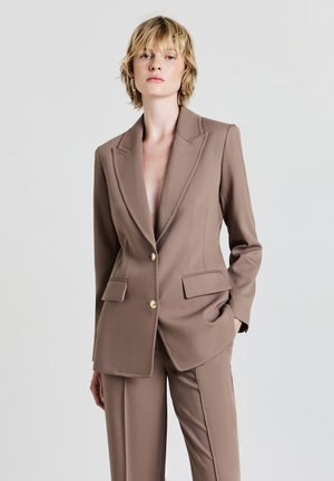 Brauner maßgeschneiderter Blazer mit goldenen Knöpfen, scharfen Revers und vorderen Taschen, kombiniert mit passenden Hosen, mit einer glatten Stofftextur.