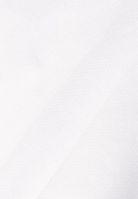 Tissu blanc avec un motif texturé subtil composé de petits triangles en relief créant une surface douce et tactile.