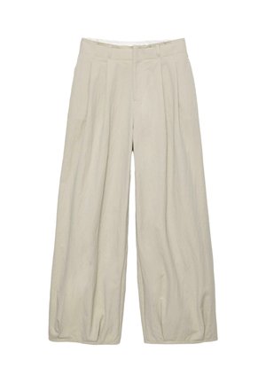 Pantalons larges beiges avec une surface texturée, dotés de plis avant et d'une taille ajustée. Pas de fermetures ni de poches visibles.