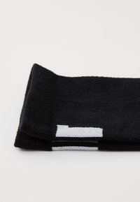 Must mustripe pealehakk toega spordipeapael; valgetes aktsentides ja logo detailiga; volditud disain kohandatava sobivuse jaoks.