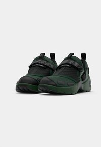 Groene en zwarte sport schoenen met een textuur mesh bovenkant, gevoerde banden en een rubberen zool met een onderscheidend ontwerp en logo detail.
