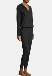 Czarny zestaw dresowy składający się z kurtki z kapturem na zamek oraz zwężanych spodni. Gładka tekstura z elastycznym pasem, zaprojektowany z myślą o komforcie.