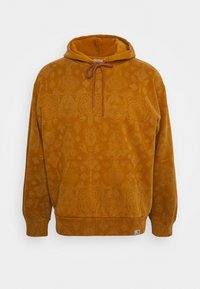 Felpa con cappuccio foderata in pile di colore giallo senape, caratterizzata da un motivo tessile sottile, tasca anteriore e cappuccio regolabile con coulisse.